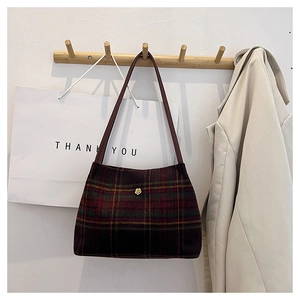 Detail view of plaid wool tote bag with golden flower accent and retro pattern texture