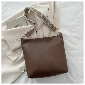 Detail of dark brown leather bag with retro patterned wide strap and gold hardware hooks