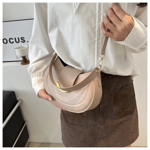 Detail view of a beige semi-circular leather crossbody bag with curved gold metal buckle