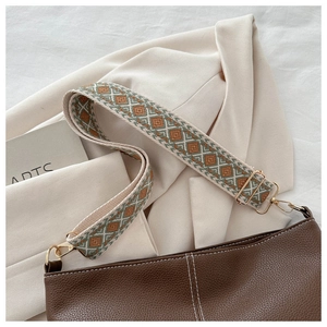 Detail of retro geometric woven strap with gold metal hooks on brown leather bucket bag