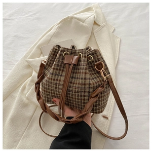 Détail du sac seau à carreaux marron avec cordon en cuir et œillets métalliques dorés