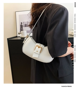 Chic white crescent shoulder bag with golden buckle shown on model in a modern setting