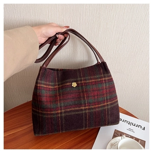 Close-up of retro plaid tote bag with wool texture and golden flower metal detail