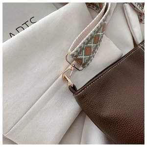 Detail of brown litchi leather bag with jacquard strap and golden metal hardware