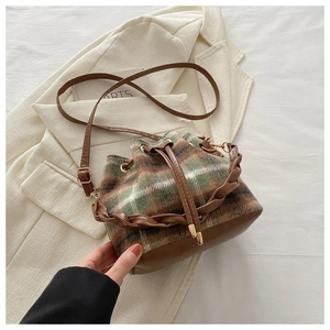 Détail d'un sac seau à carreaux avec fermeture à cordon et poignée tissée texturée