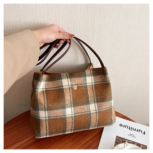 Detail of vintage plaid wool tote bag with a golden floral clasp and brown leather handle