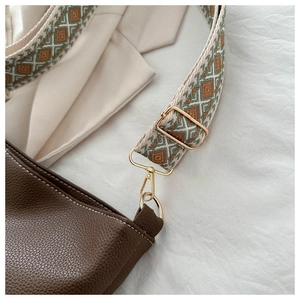 Detail of brown litchi pattern leather bag with vintage jacquard woven shoulder strap