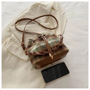 Gros plan d'un sac seau vintage à carreaux verts et marron avec base en cuir sur un blazer