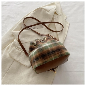 Détail du tissu en laine à carreaux et cordon en cuir sur ce sac seau élégant