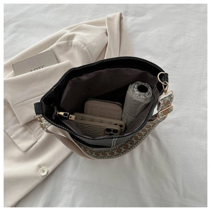 Interior view of black bucket bag showing spacious capacity for phone and wallet with wide strap