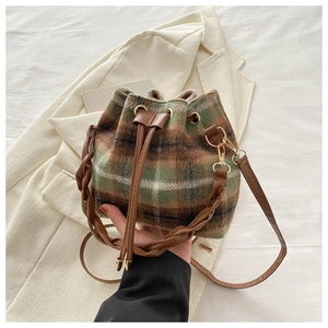 Détail du sac seau à carreaux avec texture en laine et finitions en cuir marron