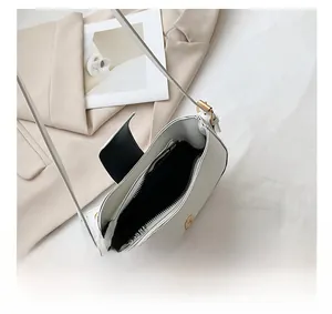 Internal view of the white square shoulder bag showing black lining and a zipper pocket