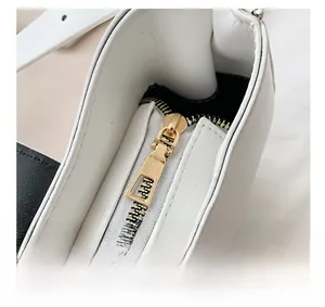 Detail view of the golden metal zipper and premium white leather texture on the handbag