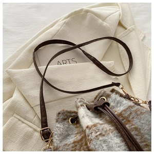 Détail du sac seau en tweed avec fermeture par cordon et boucles en métal doré