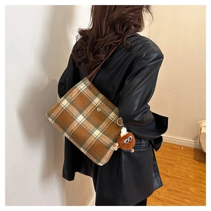 Detail of checkered wool tote bag with golden floral metal hardware and fuzzy monster charm