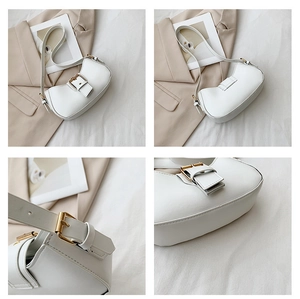 Close-up of a white leather crescent bag with golden buckle and fine stitching details