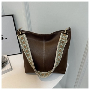 Detailed view of dark brown pebbled leather bucket bag with contrast white stitching