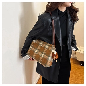 Detail of wool plaid tote bag with side fur ball pendant and slim brown shoulder strap