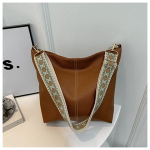 Detail of brown leather bucket bag with wide ethnic weave strap and white stitching