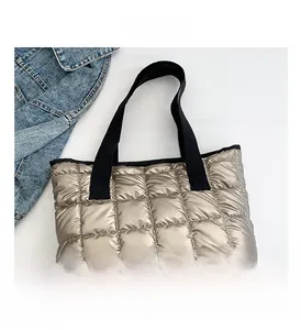 Detailansicht der champagnergoldenen gesteppten Puffer-Tasche mit schwarzen Griffen