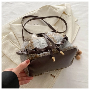 Détail de la texture peluche à carreaux et de la base en cuir marron du sac seau