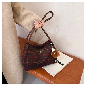 Detail of plaid wool tote bag with brown leather handles and decorative monster charm