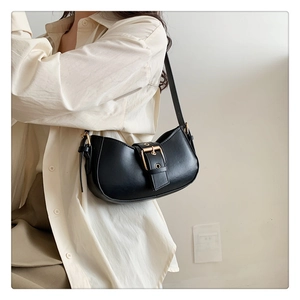 Chic black underarm bag with gold square buckle shown on model in modern interior