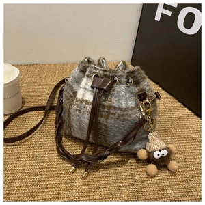 Détail du sac seau à carreaux en peluche avec cordon de serrage et breloque monstre