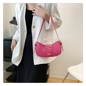 Close-up of fuchsia crescent underarm bag with large gold buckle on white blazer
