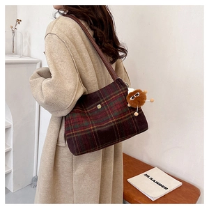 Detail of wool plaid tote bag with floral badge and plush charm on brown leather strap