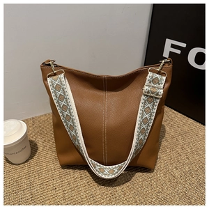 Detail of brown leather bucket bag with vintage ethnic pattern wide woven shoulder strap