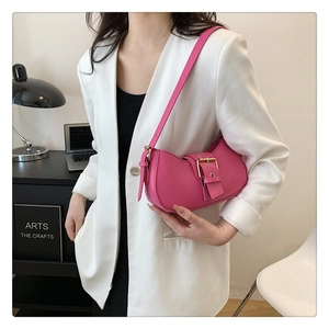 Close-up of a magenta leather baguette bag featuring a stylish gold metal buckle decoration