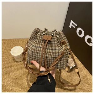 Détail du sac seau à carreaux vintage avec poignée tressée et charme en peluche