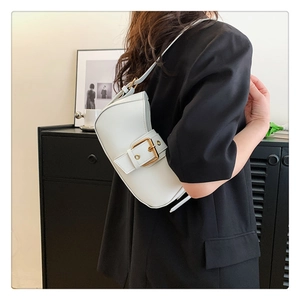 Close-up of a white crescent shoulder bag with golden buckle on a minimalist interior background