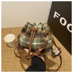 Détail du sac seau en laine à carreaux avec poignée tressée et charm peluche monstre