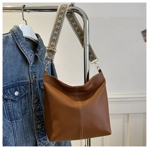 Brown leather bucket bag with white contrast stitching and a geometric jacquard wide strap