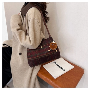 Detail of vintage wool plaid tote bag with brown leather strap and plush monster charm