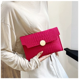 Detail of rose red crocodile pattern envelope clutch with a large gold round metal buckle