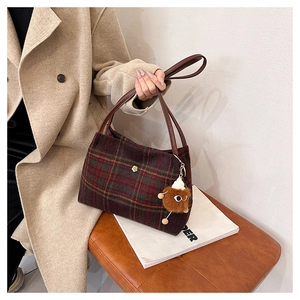 Close-up of vintage plaid tweed tote bag with leather handle and plush monster charm