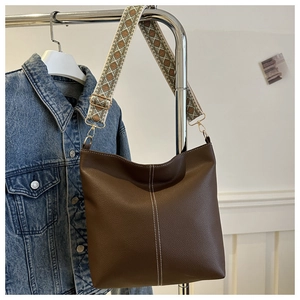Detail of dark brown lychee leather bucket bag featuring vintage jacquard wide strap