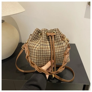 Vue détaillée du sac seau à carreaux avec poignée en cuir tressé et cordon serrage