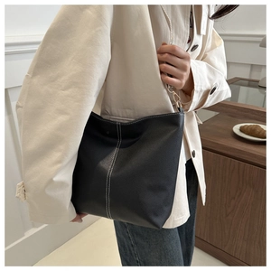 Detail showing the black lychee pattern leather and white contrast stitching of the bag