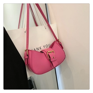 Detailed close-up of pink crescent underarm bag featuring a large gold metal buckle