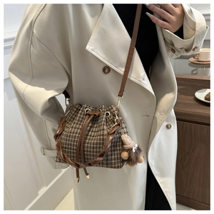 Détail du sac seau à carreaux avec poignée tressée et charm poupée en peluche