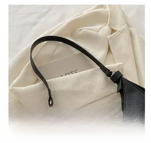 Nahaufnahme der schwarzen Ledertasche mit Litschi-Struktur und goldener Hardware