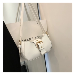 Detail of white half-moon underarm bag featuring a prominent gold metal buckle closure