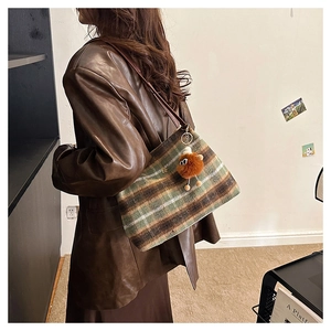 Retro striped wool tote bag with leather strap and plush charm worn by model
