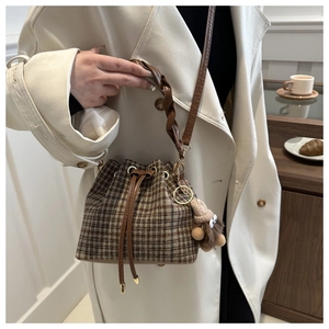 Détail du sac seau à carreaux avec cordon de serrage et poignée tissée sur mannequin