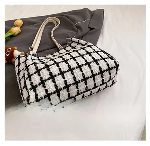 Detailansicht der Unterseite der schwarz-weiß karierten Tweed-Tasche mit Metallringen