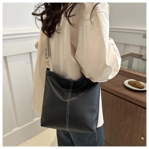 Detail of black bucket bag with white contrast stitching and wide ethnic woven strap